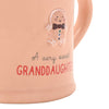Close-up of a peach-colored ceramic mug with a gingerbread man decoration and the text 'A very sweet GRANDDAUGHTER' on a white background.