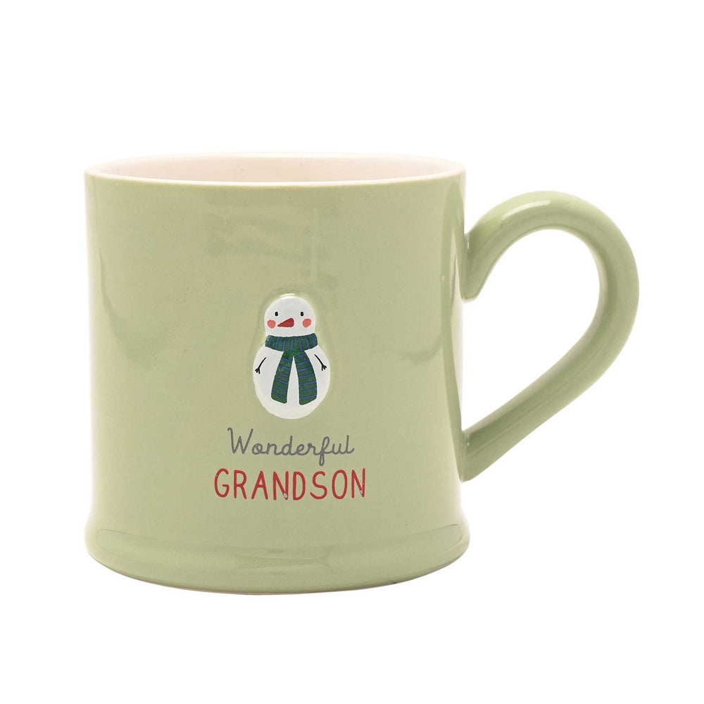 A light sage green ceramic mug with a pink interior, featuring a snowman graphic and the text 'Wonderful GRANDSON' on the front.