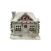 A small Santa's Cabin Christmas ornament with snow-covered gray siding, a lit window, wreath, bird feeder, and a deer on the porch, shown on a plain white background.