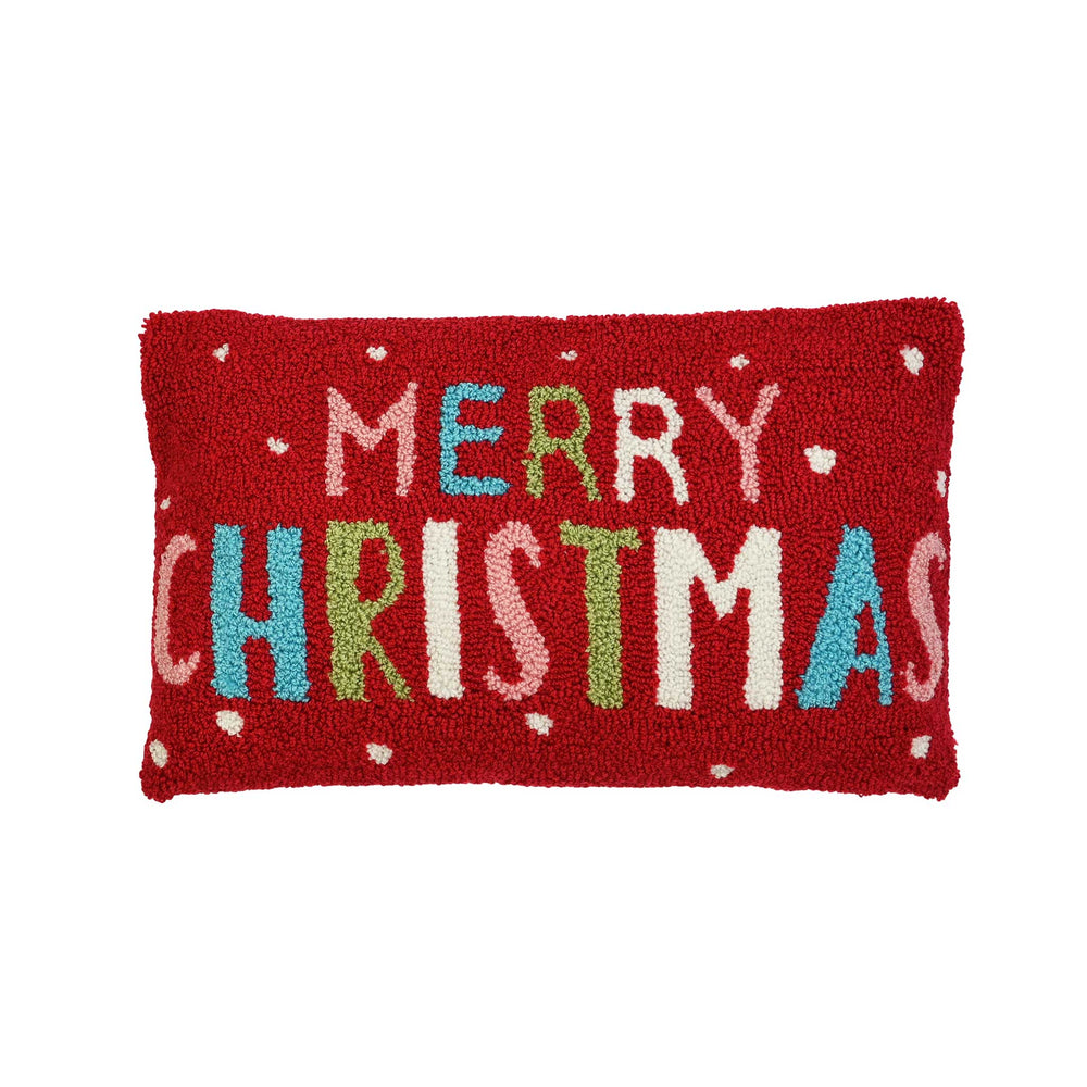A rectangular red textured throw pillow featuring the words 'MERRY CHRISTMAS' in multicolored letters with small white dot accents, shown against a plain white background.