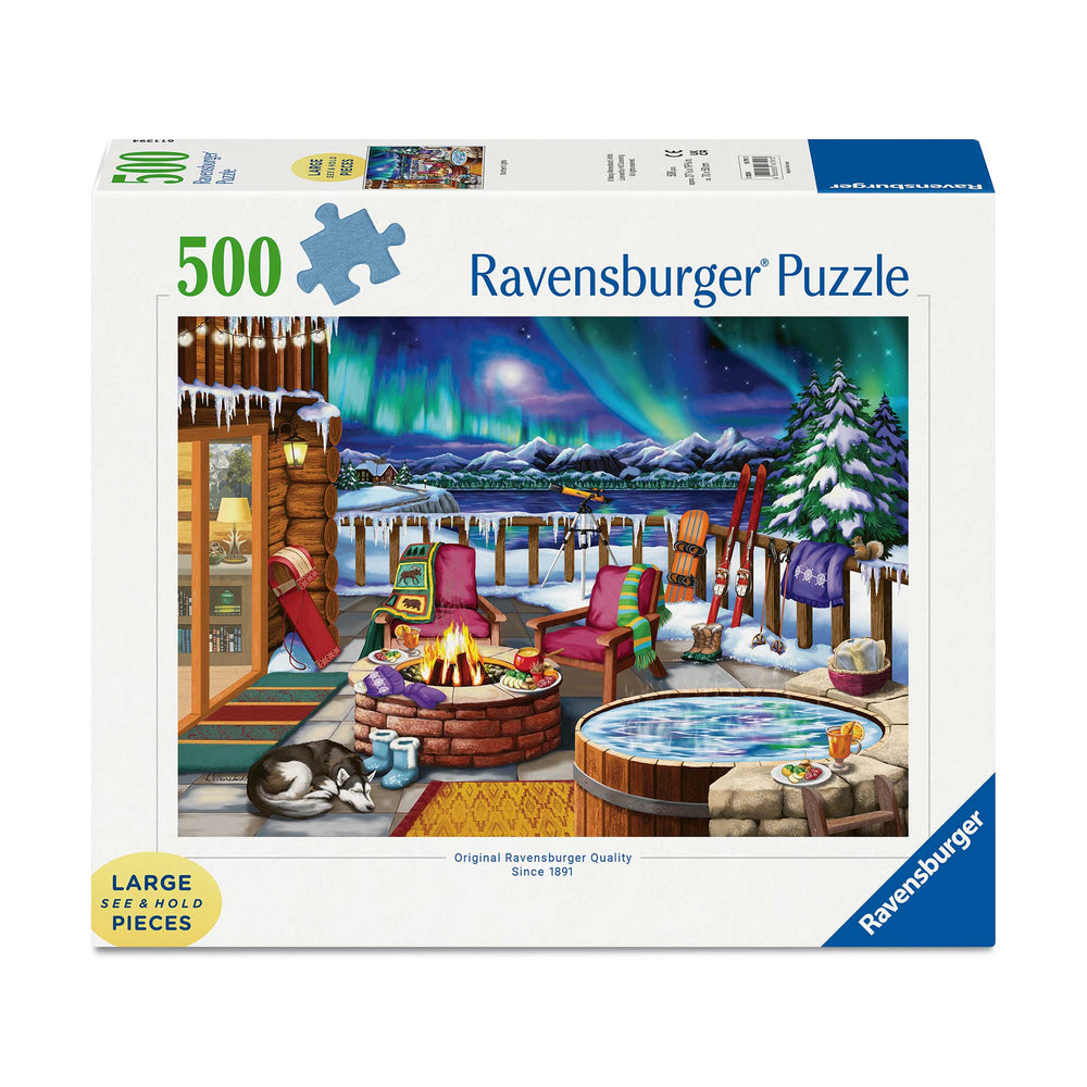 Ravensburger 500-piece jigsaw puzzle box featuring a cozy winter lakeside cabin scene with an aurora borealis sky, snowy mountains, a hot spring, and outdoor furniture.