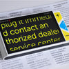 Clover 5 handheld video magnifier on a magazine showing yellow text on black background