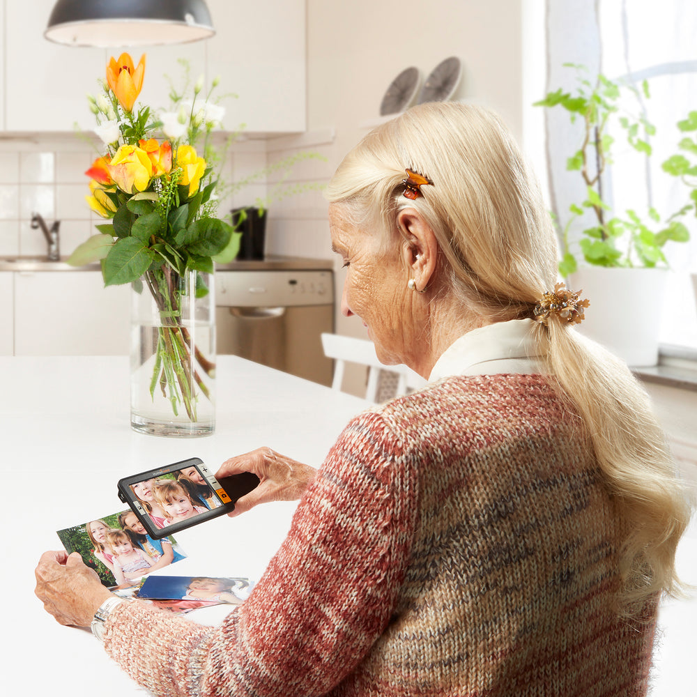 A woman using the Explore 5 handheld video magnifier to look at a photo