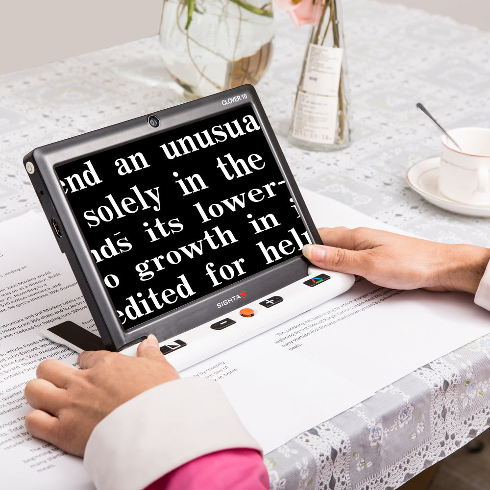 Clover 10 portable video magnifier showing enlarged text on screen in white on black format