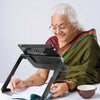 An older woman in red and green sari uses the Explore 12 to read a book at a table