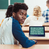 A young black student looks away from the chalkboard in class to the camera. On his desk is a Compact 8 HD showing a magnified view of text on the board.