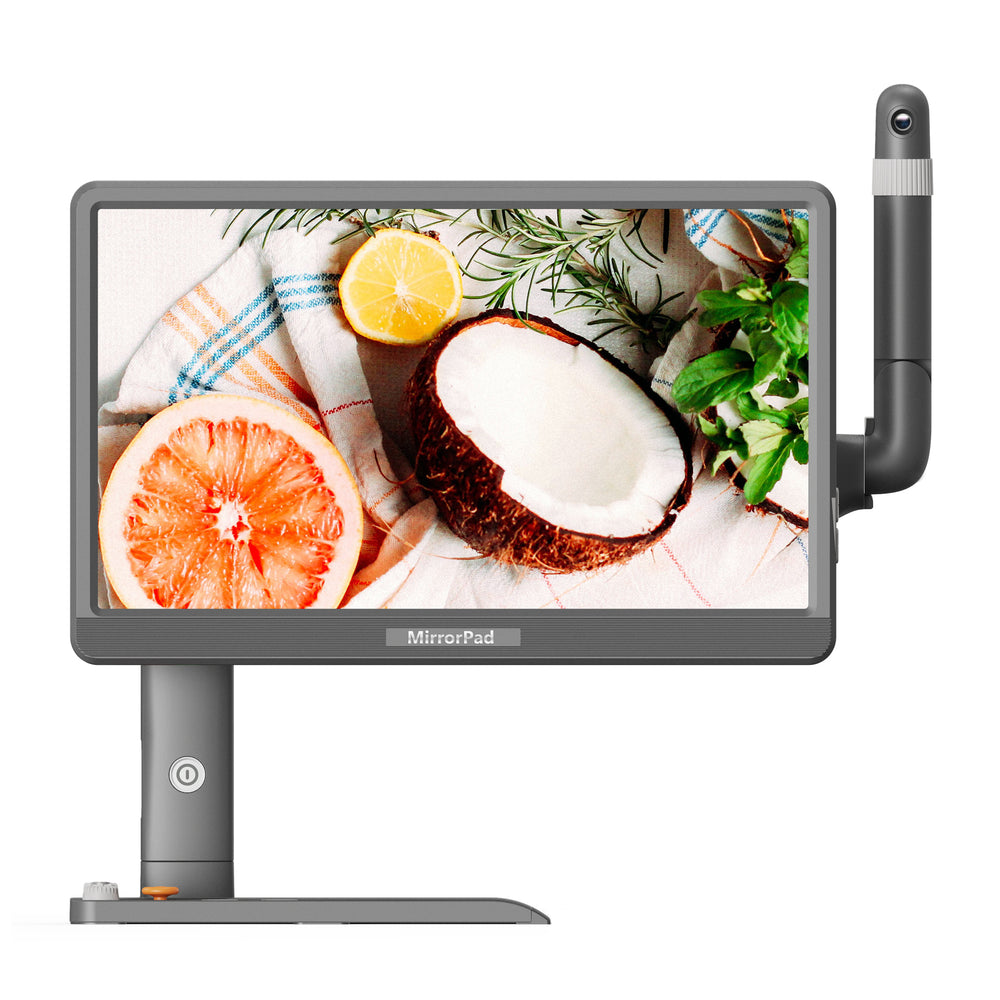 A MirroPad monitor with a vertical mounting arm, shown on a clean white background. The screen displays a colorful image of a halved coconut, a sliced grapefruit, and herbs.