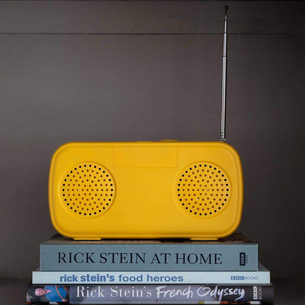 Yellow radio on a stack of books with a grey background