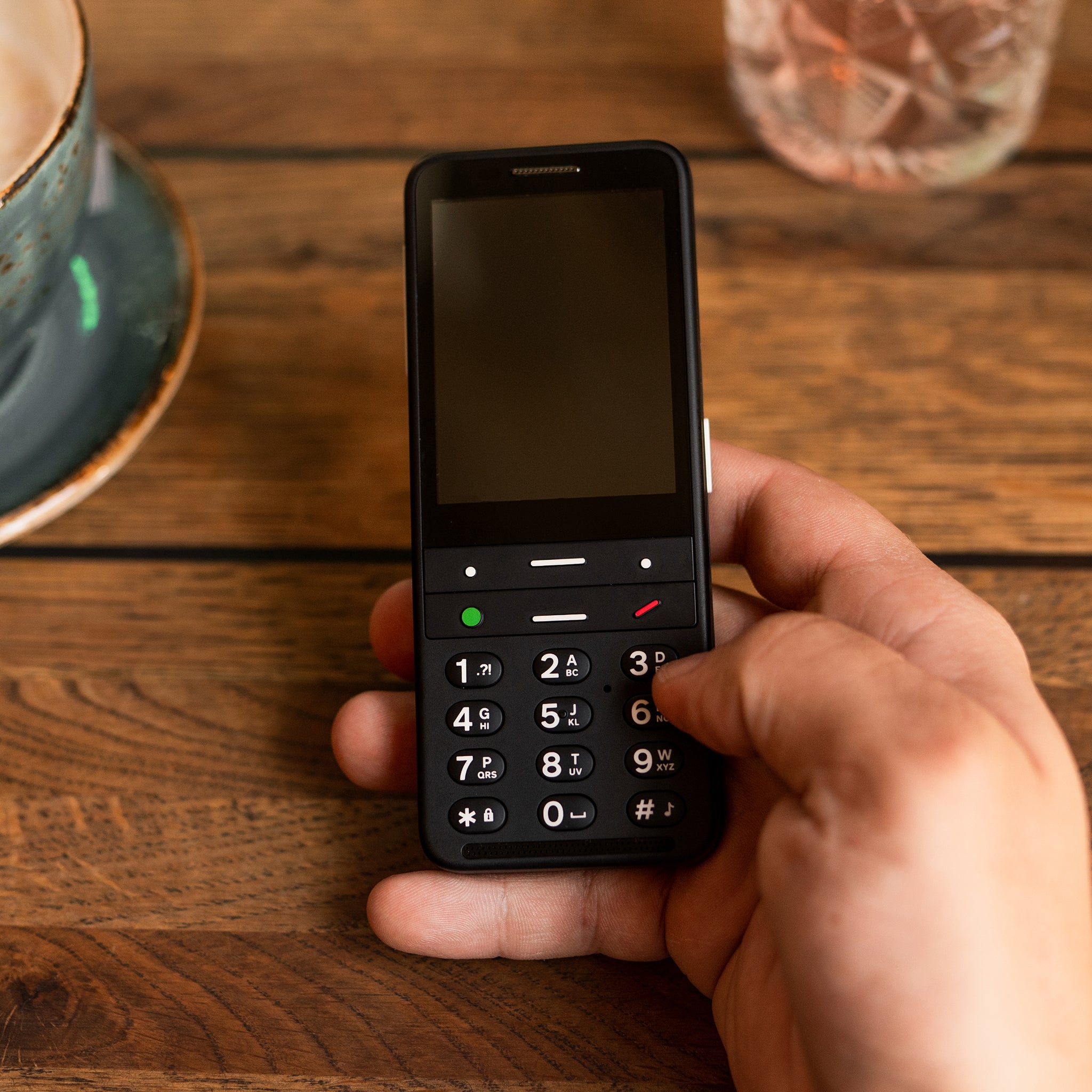 Black BlindShell Classic 2 in a person's hand at a cafe table