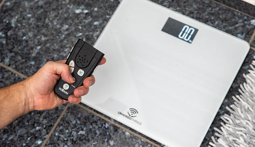 Hand holding the IKONN controller near the paired bathroom scales to hear the weight announced.