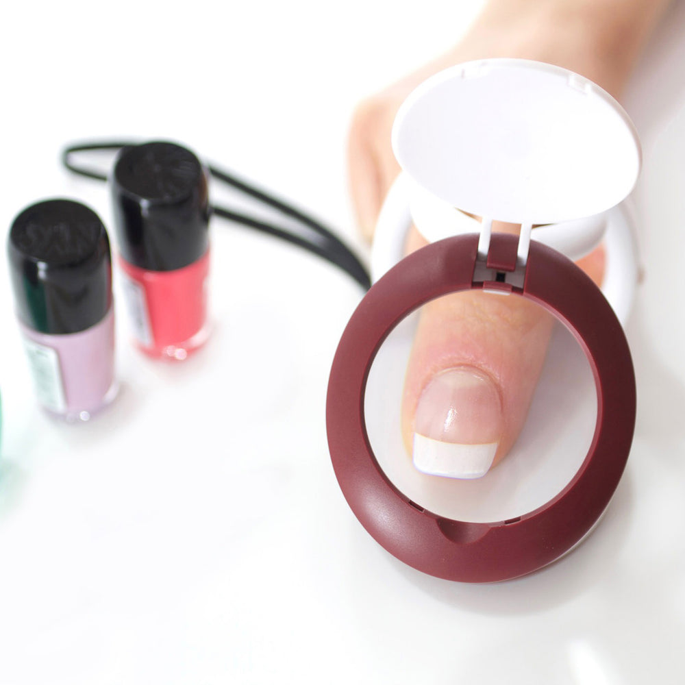 Magnifier positioned over a finger with nail polish nearby