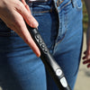 A close-up of a person wearing jeans and holding the WeWalk 2 in their hand