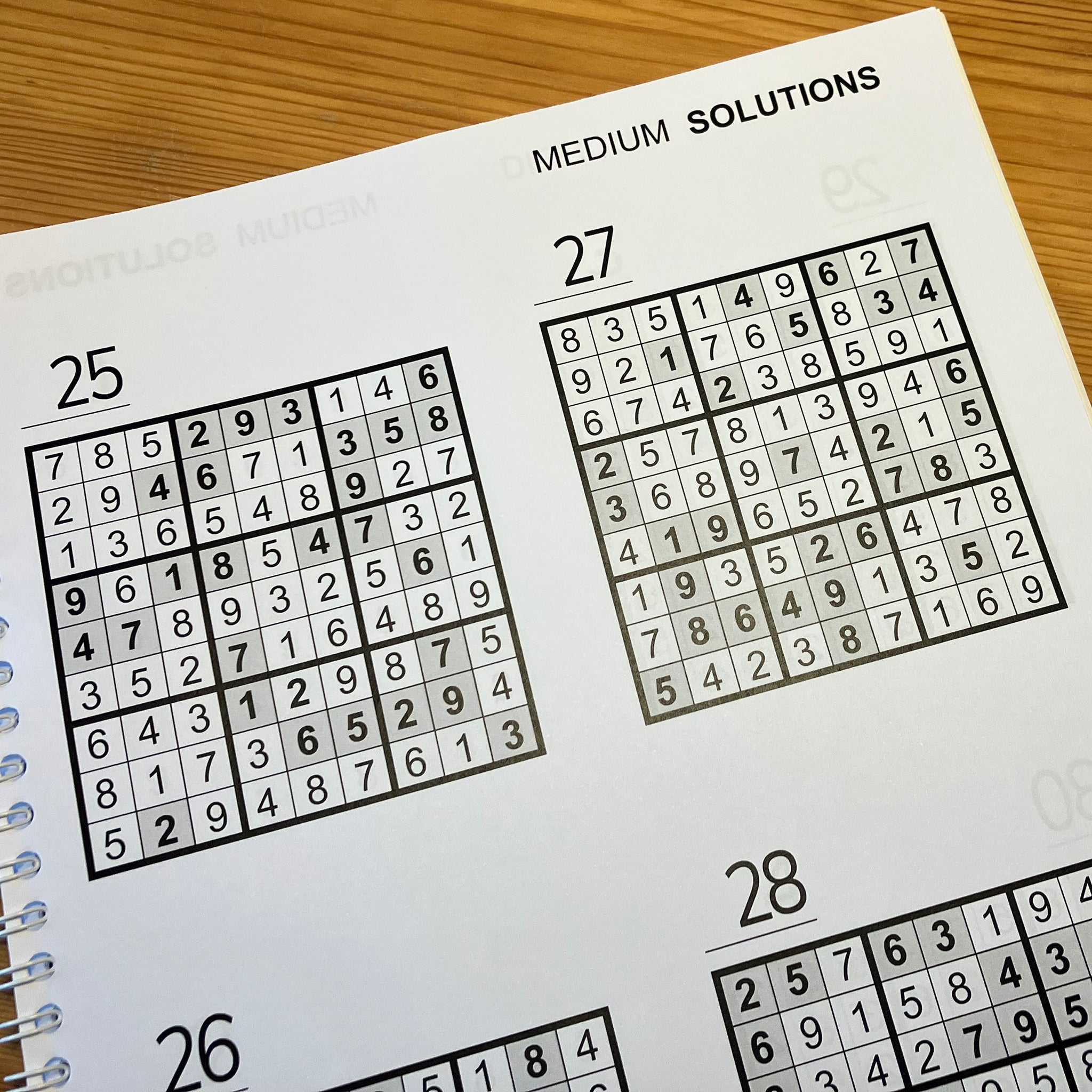 Sudoku puzzle book sowing puzzle solutions on a wooden surface