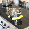 Two yellow Pan Pickles holding an empty pot in place on an induction hob