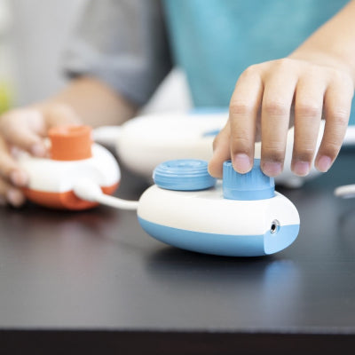 Child's hand turning the dials on the Play pod