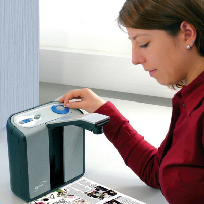 A woman using an Optelec ClearReader to read a book