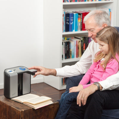 A man and child using an Optelec ClearReader to read a book