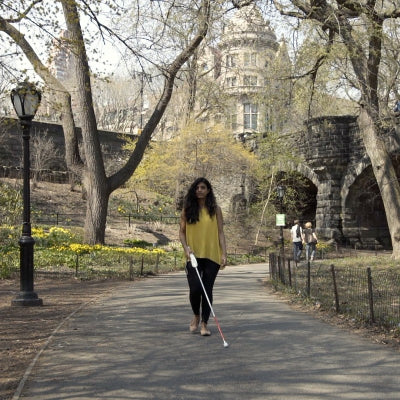 Image shows a woman walking in the park using a wewalk