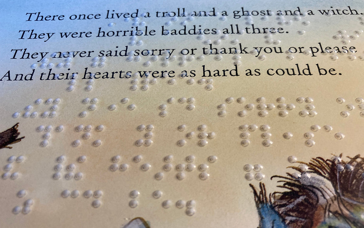Close-up of clear braille overlay and illustrated page of children's book underneath