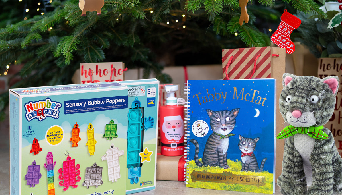 Toys, children's books and wrapped gifts beneath a decorated Christmas tree