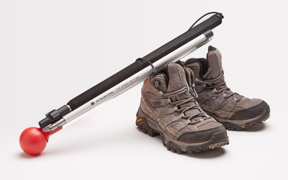 A pair of hiking boots with an all-terrain cane resting on them