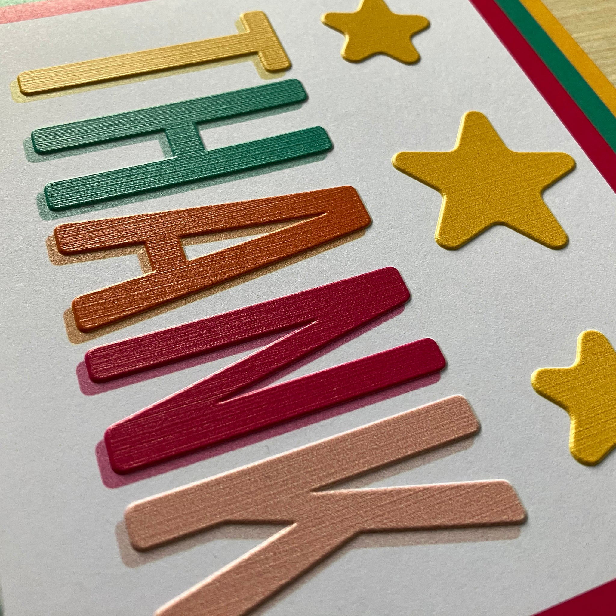 Side angled view of the thank you card showing a close up of the yellow stars and different coloured letters.