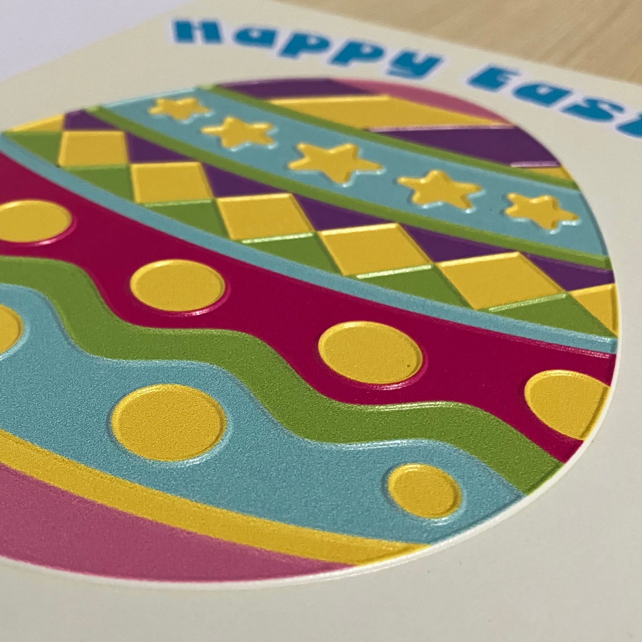 Colorful Easter egg design with geometric patterns on a card, featuring the text 'Happy Easter'.