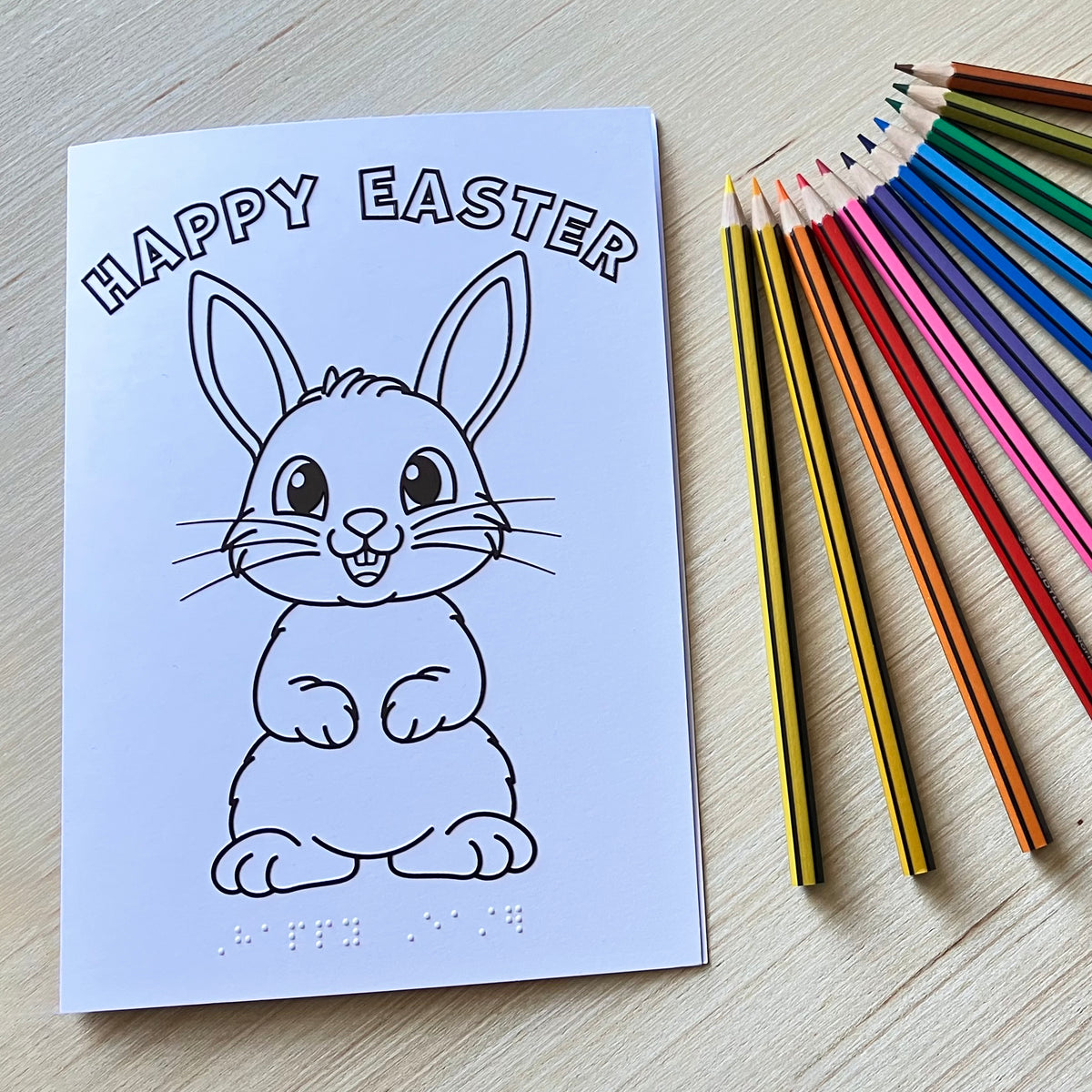 Colour-in tactile Easter bunny card on a table with colouring pencils