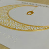 Decorative card with gold crescent moon and Arabic text on a white background
