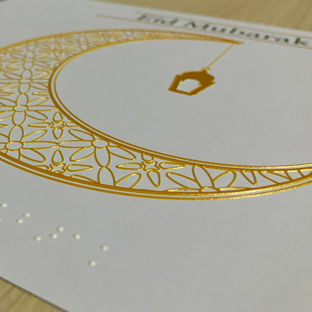 Decorative card with gold crescent moon and Arabic text on a white background