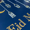 Close up of card with gold 'Eid Mubarak' text and lantern designs