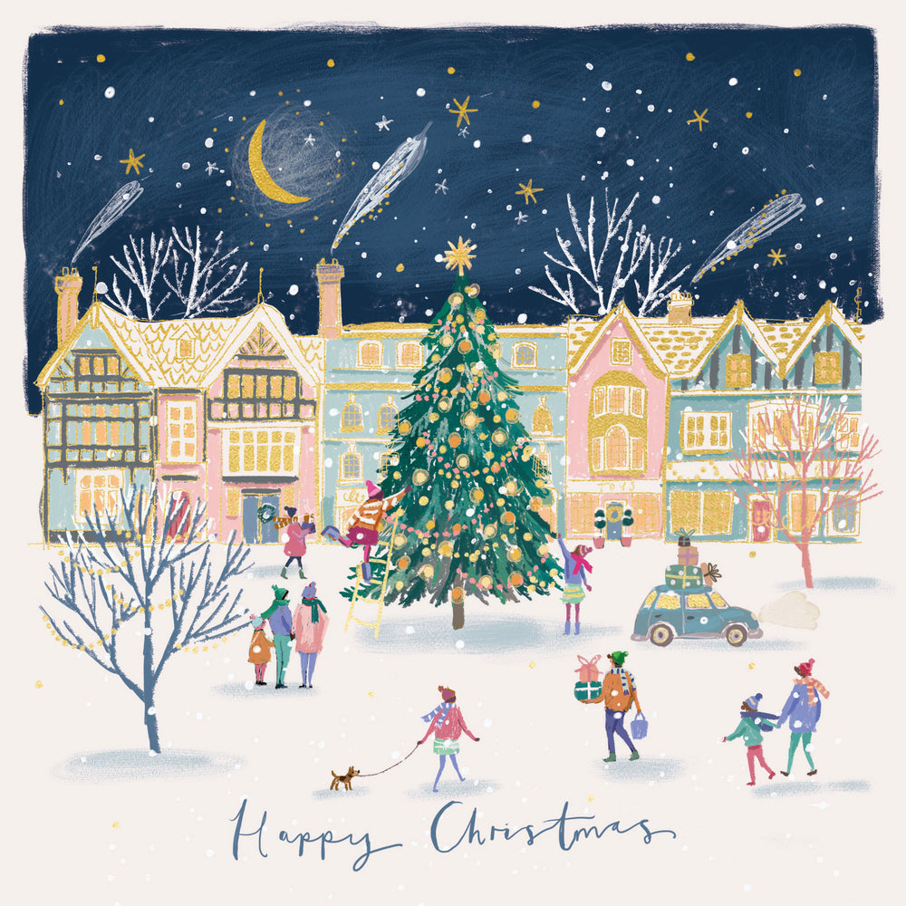 A festive illustrated winter village scene with colorful houses, a decorated Christmas tree, small people walking and gathering, shooting stars in the night sky, and the words 'Happy Christmas' at the bottom.