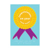 Pale blue card with golden yellow rosette with purple ribbons. Message in white text and braille reads 'Congratulations on your exam results'