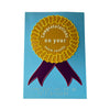 Pale blue card with golden yellow rosette with purple ribbons. Message in white text and braille reads 'Congratulations on your exam results'