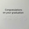 A square card or print with the text 'Congratulations on your graduation' in black text with braille lettering.