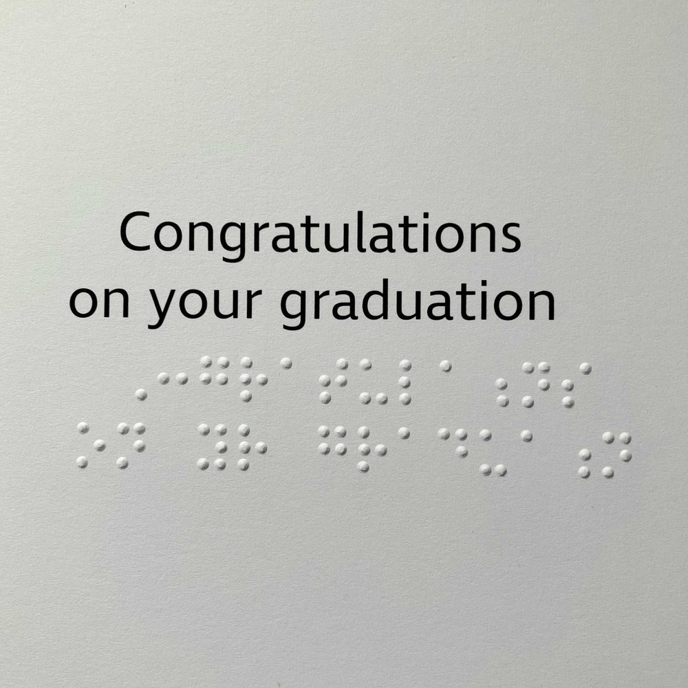 A square card or print with the text 'Congratulations on your graduation' in black text with braille lettering.