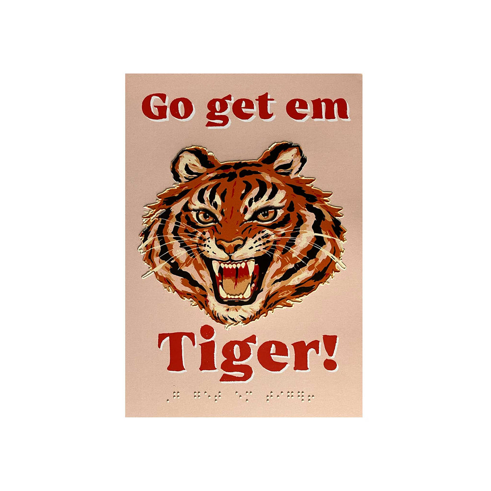 A vintage-style poster featuring a roaring tiger head centered on a pale peach background, with the words 'Go get em Tiger!' in red at the top and bottom. Braille text appears near the bottom.