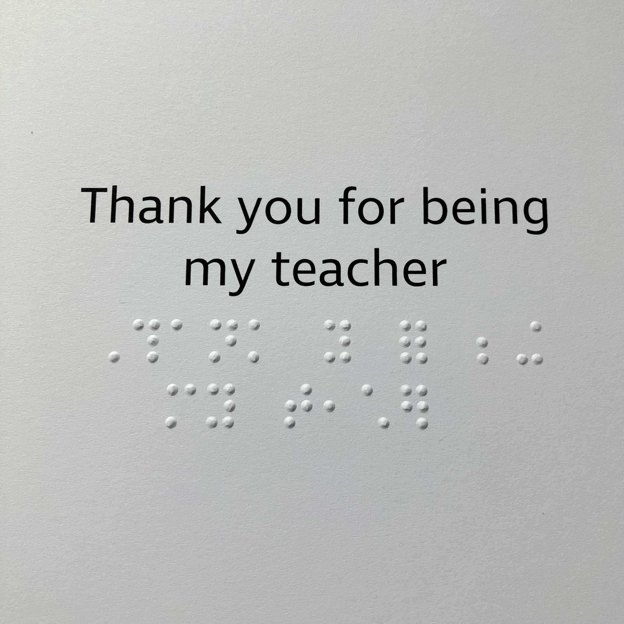 Card with the phrase 'Thank you for being my teacher' in black text with braille text, shown against a plain white background.