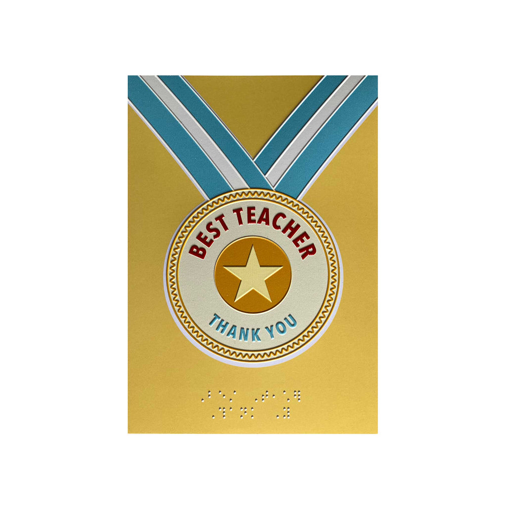 A gold greeting card featuring a medal design with a blue and white ribbon, a gold star, and the words 'BEST TEACHER THANK YOU'. The card also includes Braille text at the bottom.