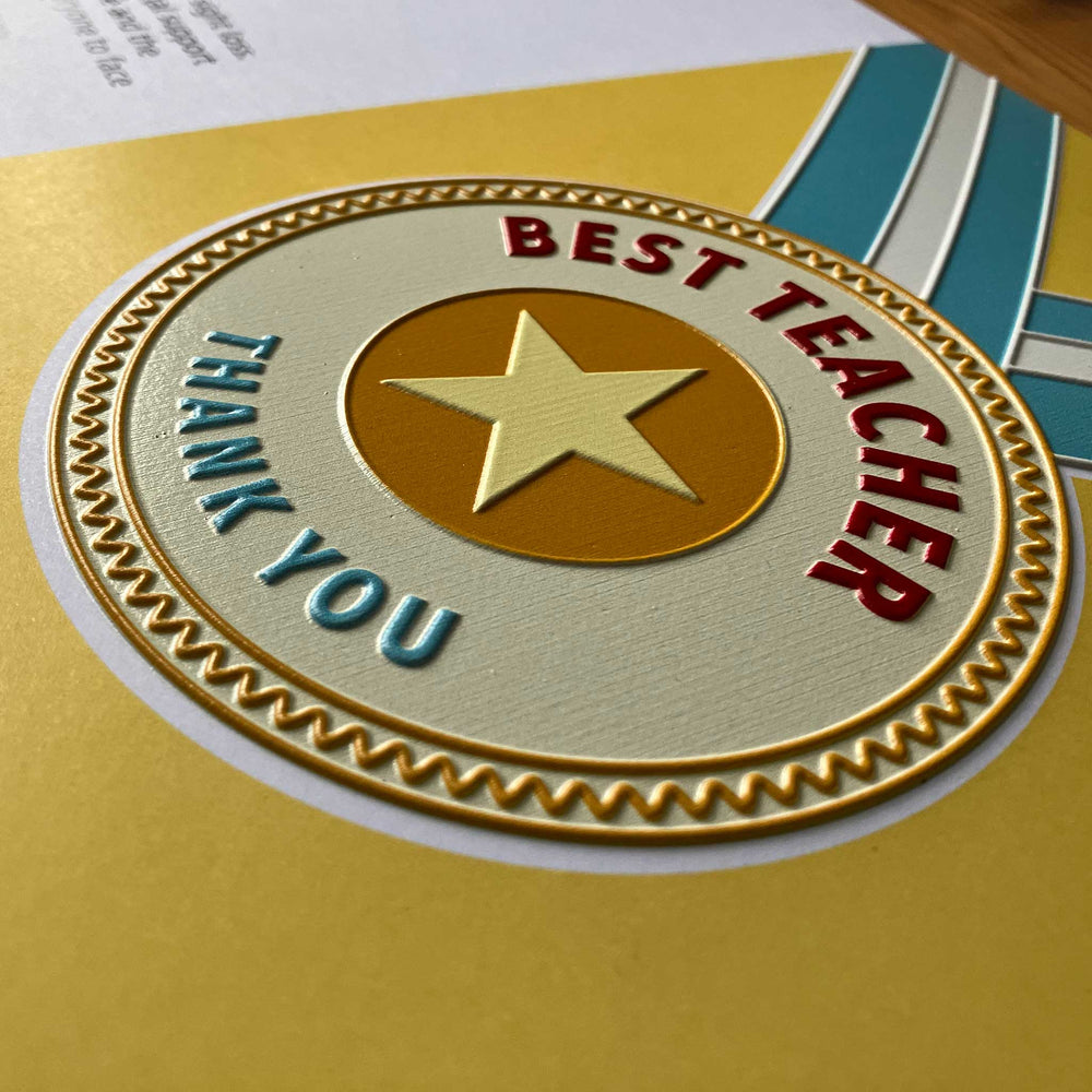 A close-up of the card or with a gold embossed star, red 'BEST TEACHER' text, and blue 'THANK YOU' text on a yellow background.