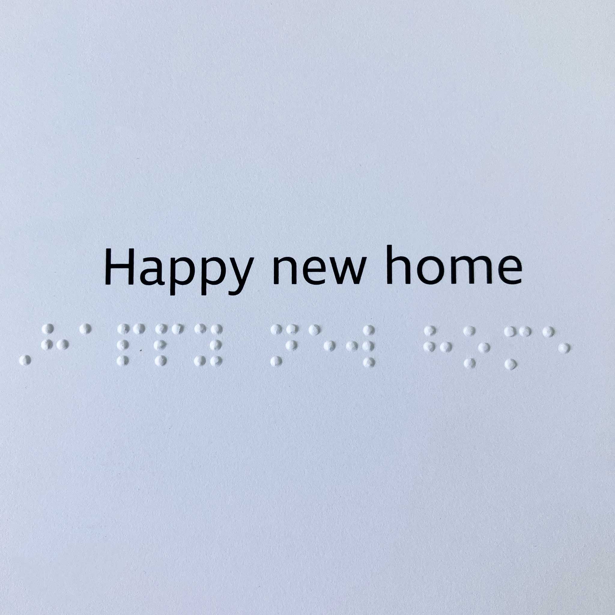 'Happy new home' in clear black text above the same message in contracted braille.