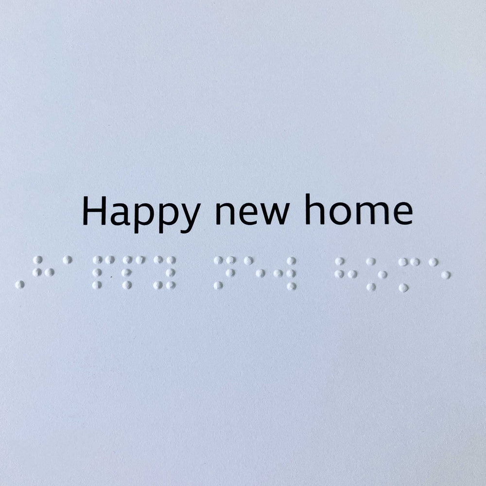 'Happy new home' in clear black text above the same message in contracted braille.