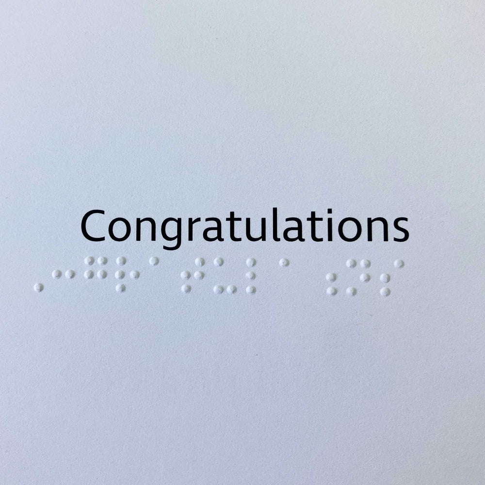Card greeting 'Congratulations' in black text above contracted braille.