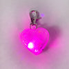 Heart-shaped light-up dog tag on white background with pink light flashing