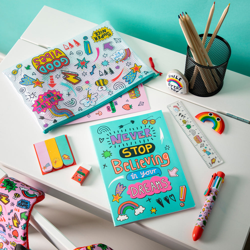 Colorful stationery items including notebooks, pens, and erasers on a white surface with a teal background.