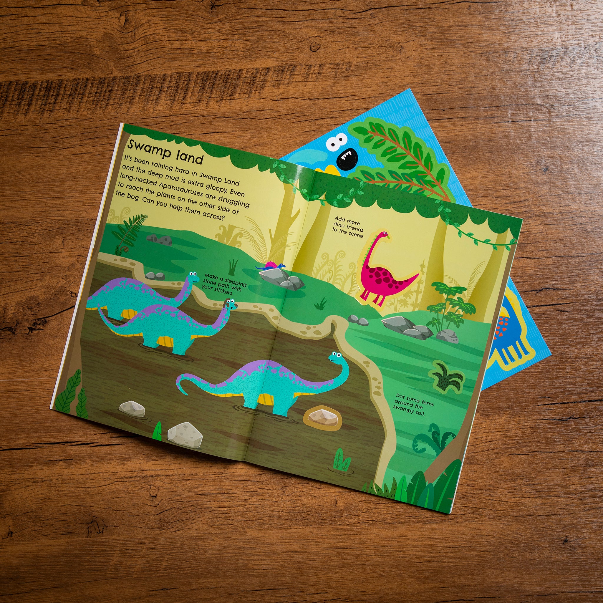 Children's dinosaur-themed activity book on a wooden surface
