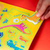 Colorful dinosaur-themed book with a hand interacting with the pages on a red background