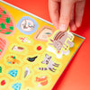 Hand placing a sticker of a warthog onto a colorful board game with animal illustrations.