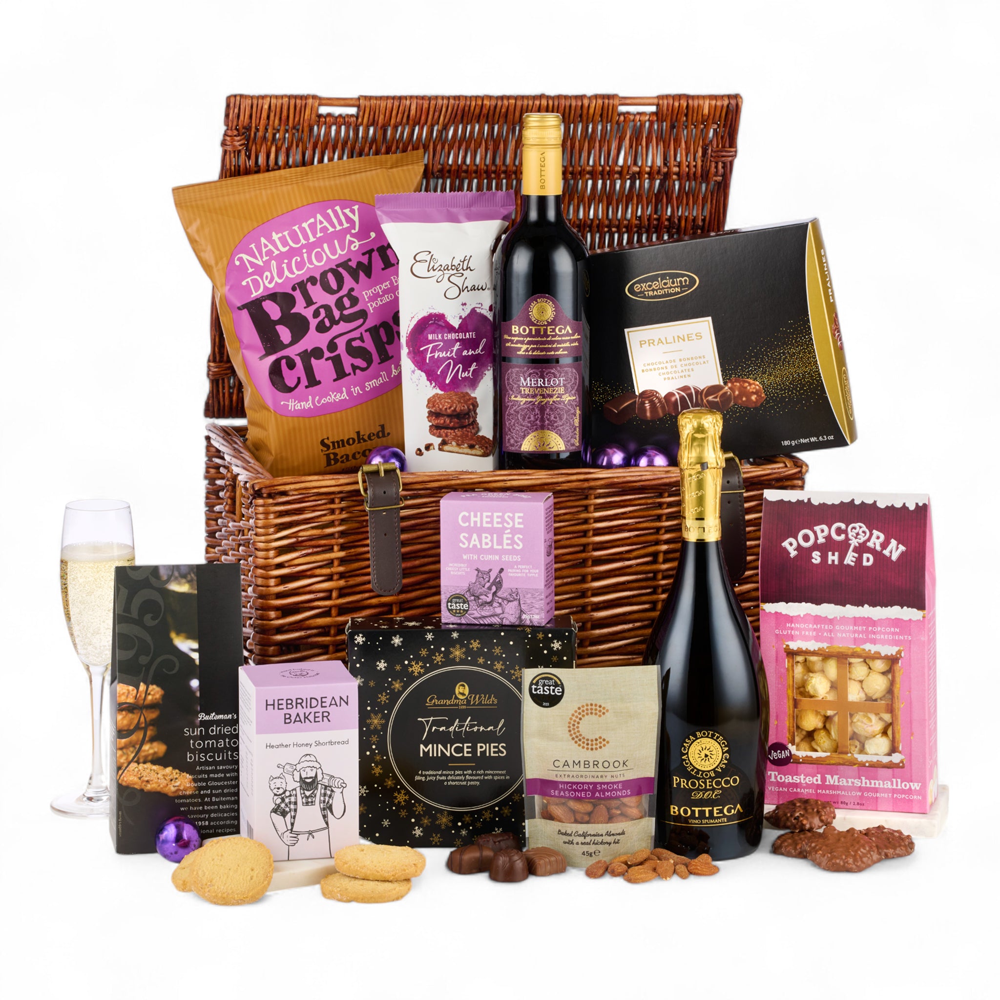Gourmet gift basket with wine, snacks, and other treats on a white background