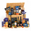 Wicker hamper filled with various snacks, cheeses, and bottles of wine on a white background
